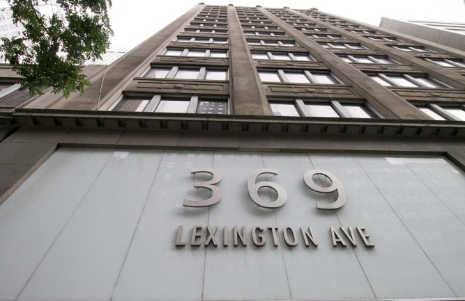 Backlit stainless-steel lettering on the building's white-etched glass facade